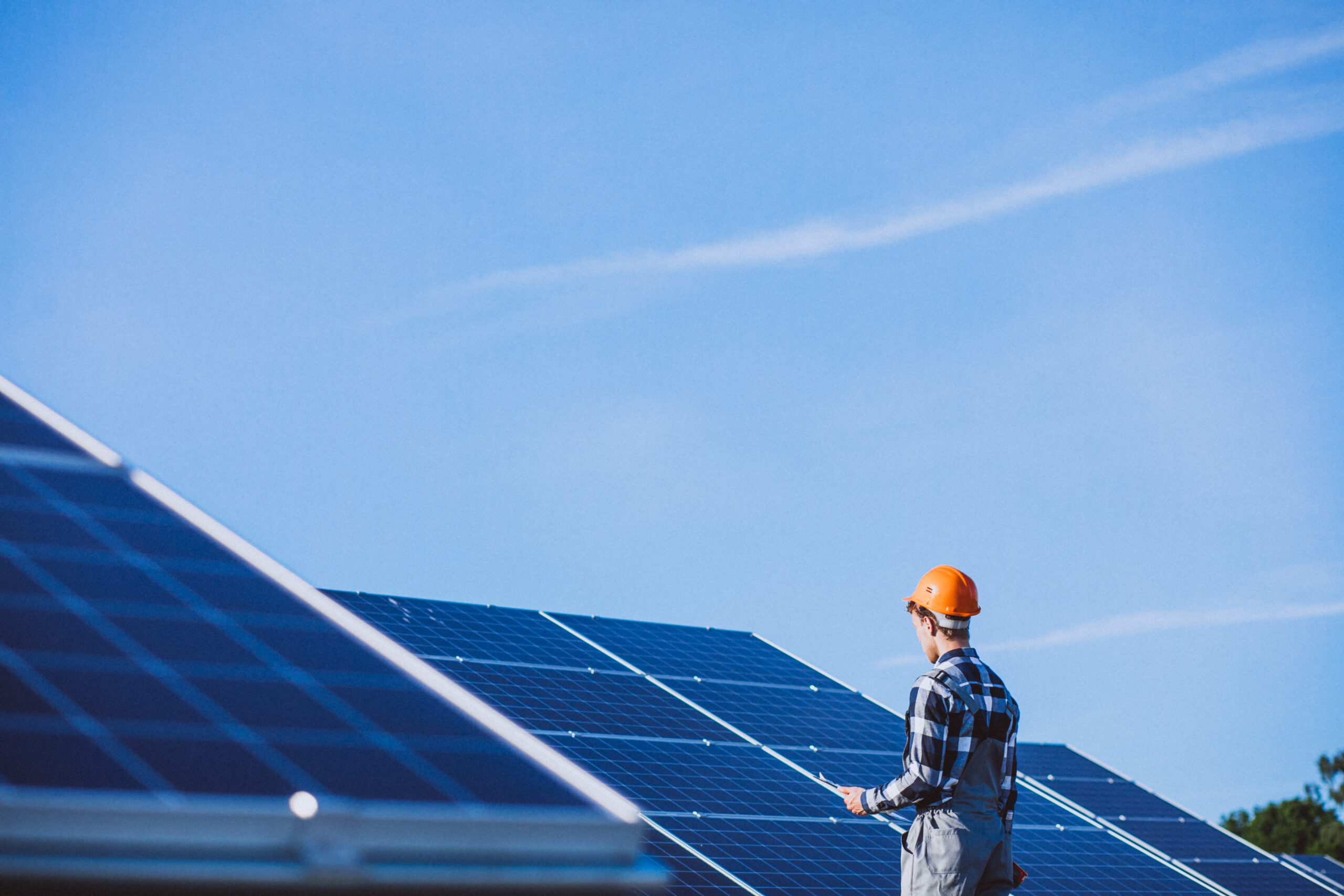 Worker standing beside Solar Panels in a renewable energy field